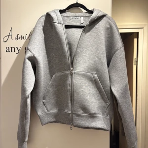 Grå hoodie med dragkedja från Weekday - Snygg grå hoodie från Weekday i storlek XS. Tröjan har huva, tvåvägsdragkedja och stora fickor framtill. Köpte koftan och var inte min stil helt och hållet så är helt ny aldrig använd, skriv vid funderingar och annat 