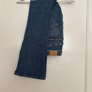 Blå bootcut jeans - Snygga blå jeans från ginatricot med klassisk femficksdesign och bootcut-ben. Jeansen är mid/high waist och är tillverkade i stretchigt denim för en bekväm passform. Perfekta för dig som gillar en tidlös look med lite utsvängda ben.