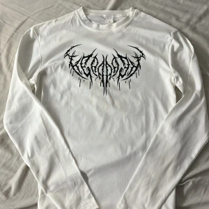 Vit långärmad tröja med svart tryck - Compression  - Säljer en vit långärmad tröja i mjukt material med ett fett svart tribal-aktigt tryck på bröstet. Tröjan har rund hals och clean baksida utan detaljer. Perfekt för dig som gillar edgy streetstyle och vill sticka ut.