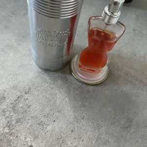 Jean Paul Gaultier  EdT - Säljer en parfym från Jean Paul Gaultier. Doften har inslag av vanilj, apelsinblomma och ingefära. Flaskan är genomskinlig och levereras i en metallisk silverfärgad burk.