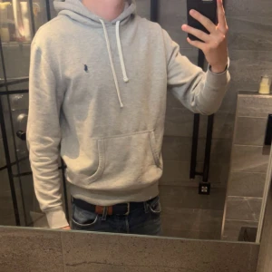 Grå hoodie från Polo Ralph Lauren - Hej! Säljer denna hoodie ifrån Polo Ralph Lauren. Tröjan är i storlek S men passar bra i M också. Hoodien har även qr kod! Tröjan kostar 2295:- ny på Ralph laurens hemsida. 