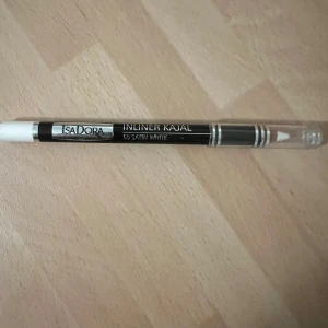 IsaDora Inliner Kajal 50 Satin White - Vit kajalpenna från IsaDora i nyansen 50 Satin White. Pennan har en klassisk form med svart och silverdetaljer samt genomskinligt lock. Perfekt för att ljusa upp vattenlinjen och ge en pigg look. Enkel att applicera och smidig att ta med i sminkväskan. Lite skav och repor från att ha legat i sminkväskan annars gott skick. 