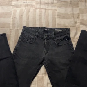 Replay Anbass svarta jeans - Säljer ett par Replay Anbass jeans i svart tvättad denim. Klassisk femficksmodell med snygga detaljer på bakfickan och Replay-logga vid myntfickan. Jeansen är slim fit och är tillverkade i bomull med en skön stretch. Perfekta för dig som gillar stilrena svarta jeans.