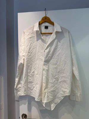 Vit skjorta från Gina Tricot - Klassisk vit skjorta från Gina Tricot med krage och knappar framtill. Tillverkad i en mjuk blandning av bomull och polyester. Långärmad och enkel design som funkar till allt.