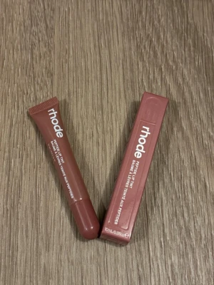 Rhode Peptide Lip Tint Toast - Helt ny Rhode Peptide Lip Tint i färgen Toast, en brunrosa nyans. Kommer i en smidig tub på 10 ml med vit text och matchande kartong