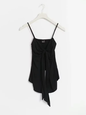 Gina knyt linne - Säljer en svart linnetopp med smala axelband och snygg knytning framtill. Toppen har en v-ringad urringning och är längre framtill för en cool asymmetrisk look. Annvänd en gång och har inga täcken på användning.