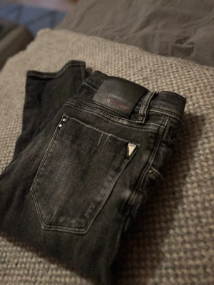Mörkgråa jeans med slitningar - Mörkgråa jeans med slitningar från Antony morato. Slim fit, storleken är 33 ska man jämföra med replay eller Jack & Jones är det som W30/31 L32-34