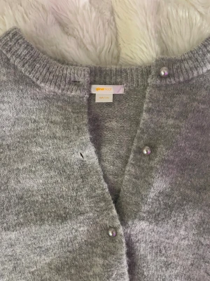 Grå stickad kofta med korta ärmar från Gina - Supersöt stickad kofta med korta armar från Gina Tricot. Koftan har pärlknappar och är i mycket bra skick. 