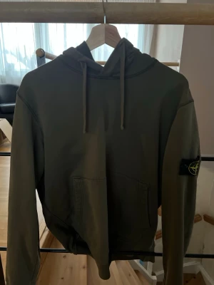 Stone Island hoodie - Grön Stone Island hoodie i mycket bra skick. Endast använd ett fåtal gånger så den är väl omhändertagen utan fläckar, hål eller andra defekter. Klassisk modell med den ikoniska Stone Island-loggan på armen. Bekväm passform och hög kvalitet.  Säljs då den tyvärr inte kommer till användning. Skicka gärna meddelande vid frågor eller om du vill ha fler bilder eller kvitto. 