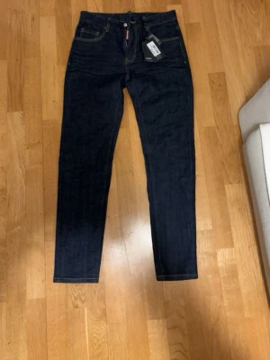Mörkblå jeans Dsquared2 - Snygga mörkblå jeans från Dsquared2 med klassisk femficksdesign och kontrastsömmar. Skinny fit med hög midja och läderpatch bak i midjan. Jeansen är tillverkade i slitstarkt denim och har dragkedjegylf samt Dsquared2-tag vid fickan. De är w31 L31 helt nya onanvända. Kan gå ner i pris vid snabb affär. Ifall frågor komm gärna pv!