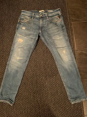 Replay ljusblå slitna jeans Slim fit  - Säljer ett par Replay jeans i ljusblå tvätt med slitningar och distressed detaljer på benen. Klassisk femficksmodell med smal passform och normal midja. Perfekta för dig som gillar en avslappnad men trendig look.