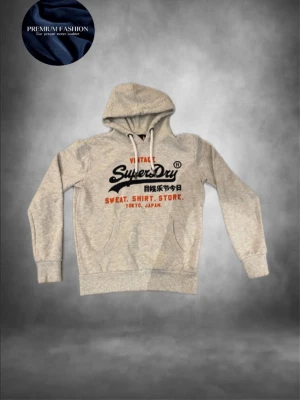 Superdry hoodie  - Tja! Säljer nu en riktigt snygg grå hoodie från Superdry med ett snyggt tryck framtill med knappast några defekter alls bara ett minimalt som inte syns på sista bilden så skicket är 9,5/10. Storlek M och passar killen på bilden som är 185! Hör av dig vid minsta lilla fundering eller fråga!🤗mvh EM_resell