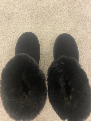Svarta boots med fuskpäls och platåsula - Säljer ett par svarta boots med fluffig fuskpäls runt skaftet och grov platåsula. Skorna är i mockaliknande material och har rund tå. Perfekta för kalla dagar när du vill hålla stilen och värmen.