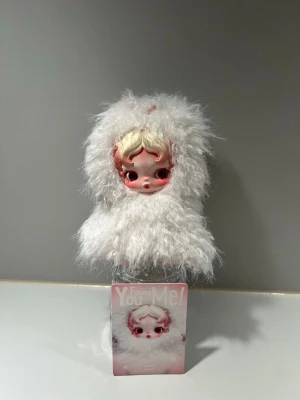 Popmart Skullpanda You Found Me Plush Keychain - Ghostie - Säljer finaste Ghostie! Denna unika docka med rörliga ögon är ett riktigt samlarobjekt och en fantastisk inredningsdetalj. Dockan är i perfekt skick. Den fluffiga dräkten är avtagbar, så just denna skullpanda är helt perfekt till att klä i olika outfits utifrån egen preferens.  Kommer med kort, ingen box  Ghostie är ett katt spöke, detta är hennes story.  ”A fluffy kitten-ghost with earmuffs, Ghostie's fur transforms fear of strangers into gentle softness, offering comfort”