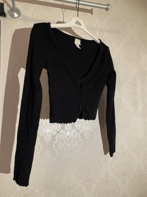 Svart croppad kofta med v-ringning - Svart croppad kofta med v-ringning och långa ärmar. 
