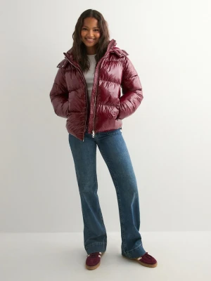 Vinröd pufferjacka från Nelly - Säljer den slutsålda vinröda pufferjackan från Nelly med glansig finish och dragkedja framtill. Jackan har hög krage och huva, perfekt för kalla dagar. Den är vadderad och har en riktigt snygg, oversized look som är både trendig och bekväm.