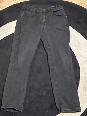 Svarta jeans från Sam's Jeans L/32 - Svarta jeans från Sam's Jeans med klassisk femficksdesign och raka ben. Jeansen har en enkel look utan synliga slitningar eller mönster, och är tillverkade i ett mjukt denimtyg. Passar dig som gillar stilrena och tidlösa byxor.