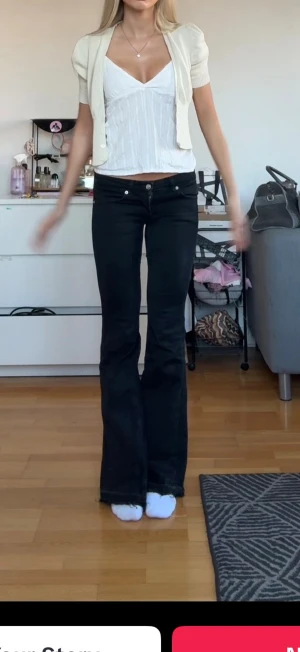 Svarta bootcut jeans med låg midja - Säljer ett par svarta jeans med bootcut-modell och låg midja. Jeansen har klassisk femficksdesign, smal passform över låren och utsvängda ben. Materialet är jeans och färgen är djup svart, perfekt för en trendig och avslappnad look.