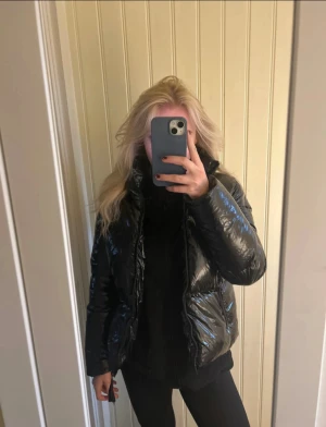 Svart pufferjacka Tommy Hilfiger S - Säljer en svart, glansig pufferjacka från Tommy Hilfiger i storlek S. Jackan har hög krage, dragkedja framtill och två fickor på sidorna. Materialet är syntet och jackan har en riktigt cool, oversized vibe som passar perfekt till kalla dagar.