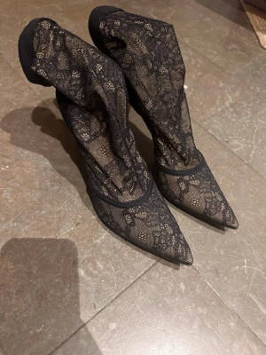 Gianvito Rossi stövletter i spets - Svarta stövletter med spetsig tå och hög klack. Skorna är täckta av transparent spets med blommigt mönster. Supersköna eftersom det är som en strumpa. Strö 39 2/3. Använt en gång. 