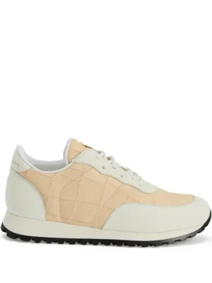 Beige och vita sneakers med quiltad detalj - Snygga sneakers i beige och vitt med quiltad textur på sidorna och vita skinnpaneler. Skorna har snörning och en svart platt sula som ger en sportig look. Perfekta för dig som gillar stilrena och moderna sneakers.