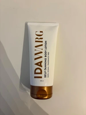 IDA WARG brun utan sol lotion - Brun utan sol body lotion från IDA WARG. Tuben rymmer 200 ml och är 100% vegansk samt parfymfri. Förpackningen är vit med guldiga detaljer och har ett brunt lock. Perfekt för en solkysst look året runt.