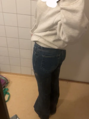 Blå bootcut jeans med hög midja - Snygga blå jeans med bootcut-modell och hög midja. Klassisk femficksdesign och raka ben som blir vidare nedtill. Perfekta för en avslappnad och trendig look. lite trasiga längst ner men inget man tänker på, å samma sak på fickan där bak. storleken finns inte kvar längre men passar mig som är i xs! 