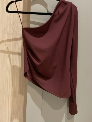 Vinröd oneshoulder topp från  Gina Tricot - Jättefin topp från Gina Tricot i storlek M, perfekt för tillfällen där man vill klä upp sig lite💗💗💗