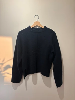 Svart stickad tröja med rund hals - En enkel och stilren blå stickad tröja med rund hals och långa ärmar. Tröjan har en rak passform och ribbade muddar vid hals, ärmslut och nederkant. Passar xs-m