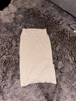 Beige ribbad långkjol - En stilren beige långkjol med ribbad struktur. Kjolen har en rak passform och är perfekt för dig som gillar en enkel och clean look. Passar till många olika outfits och är lätt att matcha.