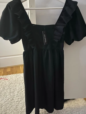 Svart volangklänning från Boohoo - Helt ny supersöt svart klänning från Boohoo med puffärmar och volangdetaljer längs ringningen💓pris kan diskuteras så lämna gärna förstag