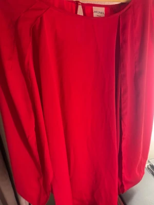 Röd klänning från Monki - Snygg röd klänning från Monki i enkel och stilren design. Klänningen har rund halsringning och långa ärmar. Tillverkad i ett mjukt och lätt material som känns skönt mot huden.