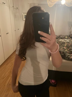 Vit basic t-shirt i bomull - En klassisk vit t-shirt med korta ärmar och rund hals. Modellen är figurnära och passar perfekt till jeans eller kjol. Tillverkad i mjuk bomull som känns skön mot huden.