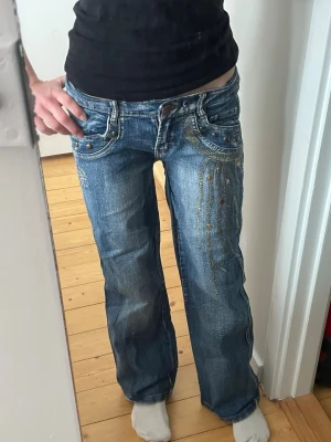 Lågmidjade jeans med detaljer 💓 - Blåa lågmidjade jeans som är lite ”lose fit”/ bootcut med coola detaljer💛 storlek s, skulle säga att de är 26/30💛 Använda fåtal gånger, inga defekter 💛skriv vid frågor !pris kan diskuteras