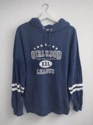 Marinblå hoodie med tryck, strlk S - En marinblå hoodie med tryck i oversize passform i storlek S från H&M DIVIDED men är köpt secondhand och är använd några gånger men fortfarande i bra/fint skick! Finns inga synliga tecken på användning vad jag kan se. FÖRST TILL KVARN!