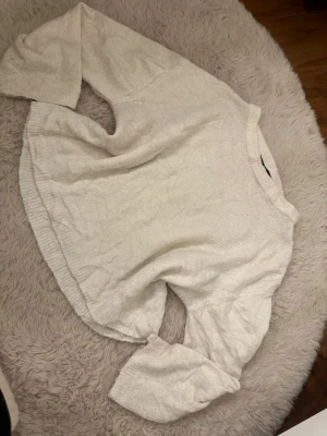 Vit oversized stickad tröja - Mysig vit stickad tröja med avslappnad, oversized passform och rund halsringning. Tröjan har långa ärmar och ribbstickade muddar vid hals och nederkant. Perfekt för lager-på-lager och chill dagar. Obs den är nopprig