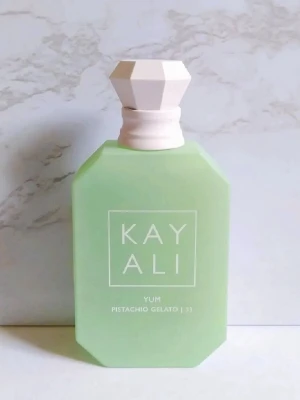 Kayali Yum Pistachio Gelato parfym - Kayali Yum Pistachio Gelato är en parfym i en stilren, ljusgrön glasflaska med vit, multifacetterad kork. Flaskan har en modern, geometrisk form och tydlig logga framtill. Doften är inspirerad av pistageglass och ger en fräsch och unik känsla. Ca 20 ml kvar! 