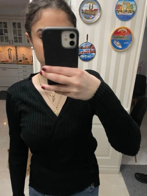 Svart kofta med snöre - En svart omlott kofta med snöre. Ribbat material.