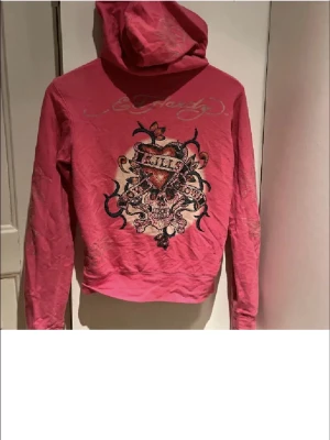 Rosa Ed Hardy hoodie med tryck - Säljer en rosa hoodie från Ed Hardy då den inte kommer till användning längre. Hoodiens dragkedja är sönder men det går nog att fixa och annars är den helt felfri!