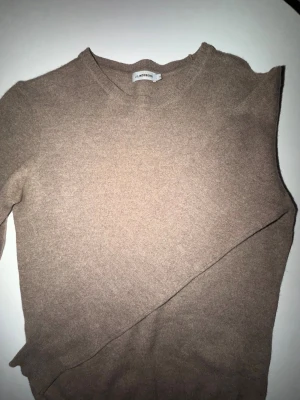 Beige stickad tröja från J.Lindeberg - En enkel och stilren beige stickad tröja från J.Llindeberg . Tröjan har rund halsringning och är tillverkad i ett mjukt, tunt material som passar perfekt till lager på lager. Klassisk modell med långa ärmar.