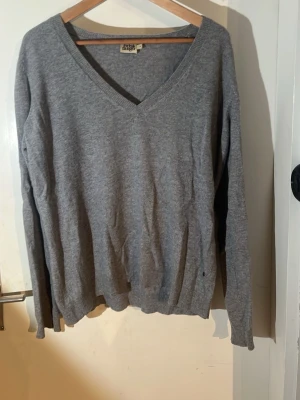 Grå v-ringad tröja Kashmir  - En enkel och stilren grå tröja från fint märke med v-ringning och långa ärmar. Tröjan har en klassisk passform och ribbade muddar vid ärmslut och nederkant. Det är 100% kashmir.