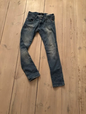 Replay Anbass blå jeans, storlek 29 - Säljer ett par Replay Anbass jeans i klassisk blå tvätt. Modellen har smal passform och fem fickor. Storlek 29. Priset är inte hugget i sten!