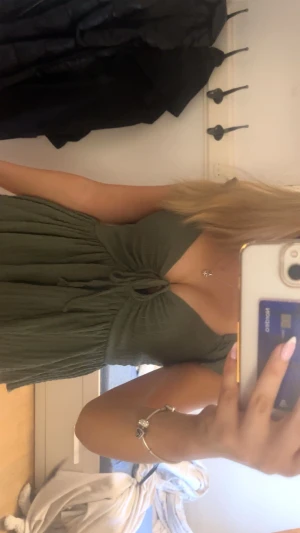 Olivgrön omlottopp med knyt - Supersöt olivgrön topp med omlottdesign och knyt framtill. Toppen har volangärmar och en lätt rynkad, flowy passform. Perfekt att styla med jeans eller kjol för en trendig look.