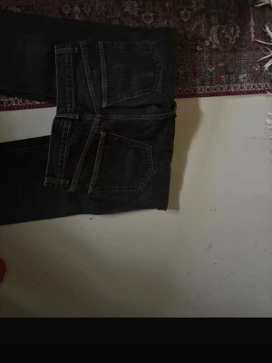 Svarta jeans från ASOS Design 28/32 - Säljer ett par svarta jeans från ASOS Design i storlek 28/32. Jeansen har klassisk femficksdesign, raka ben och snygga kontrastsömmar. Materialet är robust denim och färgen är mörk svart. Perfekt för dig som gillar stilrena och tidlösa jeans.