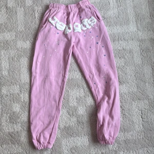 Rosa mjukisbyxor från SP5DER - Säljer ett par rosa mjukisbyxor från SP5DER i storlek S. Byxorna har resår i midjan och vid bensluten, samt en bakficka. Framtill finns ett stort vitt SP5DER-tryck och små stjärnor i blått och vitt. Materialet är mjuk bomull, perfekt för chill dagar.