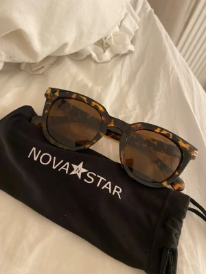 solglasögon - Bilderna visar ett par solglasögon från Nova Star med brunmelerad båge och tillhörande svart fodral. Köpte på smögen inte använt dom.
