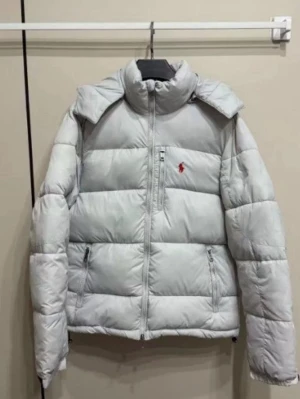 Vit pufferjacka från Polo Ralph Lauren - Säljer en fräsch vit pufferjacka från Polo Ralph Lauren med röd logga på bröstet. Jackan har hög krage, dragkedja framtill och två sidofickor med dragkedja. Perfekt för kalla dagar och har en clean, modern look.