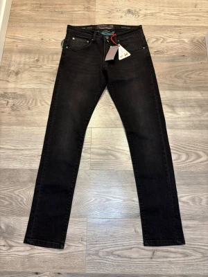 Jacob Cohen jeans - Snygga svarta jeans från Jacob Cohen med klassisk femficksdesign och diskreta detaljer. Modellen är rak och har dragkedja i gylfen samt coolt mönstrat innerfoder. Materialet är mjukt och stretchigt jeans, perfekt för dig som gillar stilren look.
