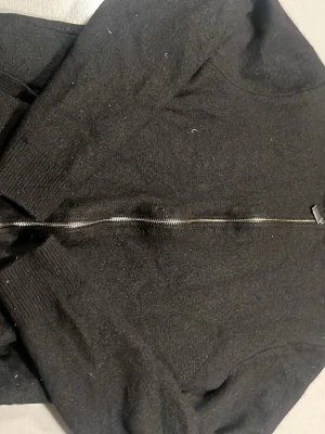 Svart stickad kofta med dragkedja - Svart stickad kofta i mediumstorlek med hel dragkedja framtill. Tröjan har långa ärmar och ribbade muddar vid ärmslut och nederkant. Perfekt för lager-på-lager under höst och vinter. Enkel och stilren design som funkar till många olika outfits. Det står M men är XS( pris går diskuteras)