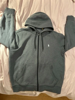 Polo Ralph Lauren, zip hoodie - En grå Ralph Lauren zip hoodie. Knappt använd och är i väldigt bra skick. Tröjan är i storlek M. Priser kan diskuteras.